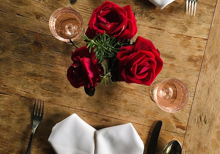 Valentinstagsbuffet in der Wein.Küche Romantisch gedeckter Tisch mit Rosen und herzförmigen Servietten.
