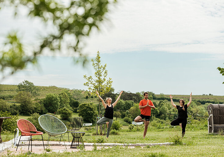 Yoga Retreat im Weinviertel Drei Personen, die im Garten vom Wein.Hotel Neustifter Yoga machen